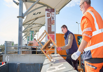 Un usagé de la déchetterie dépose une chaise en bois dans une benne réservée au bois.