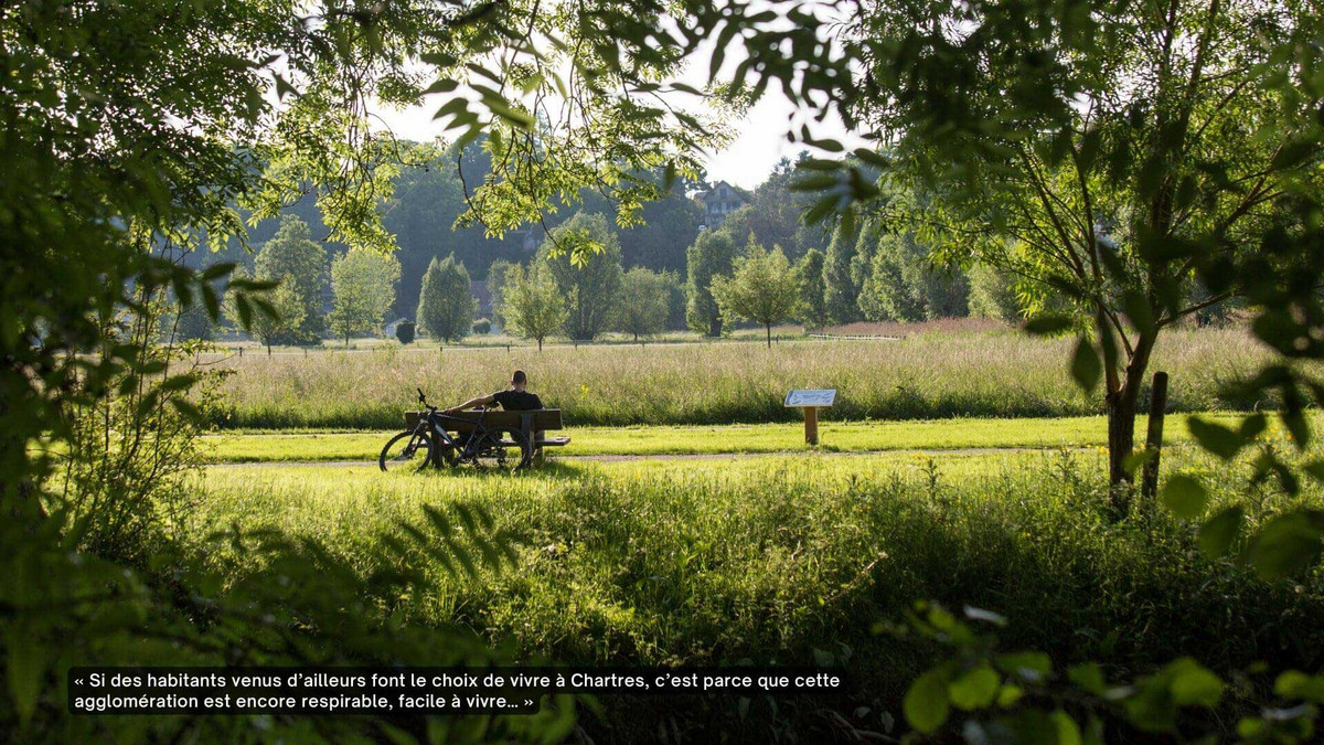 Un homme de dos, assis sur un banc entouré de végétation et à proximité d'une rivière